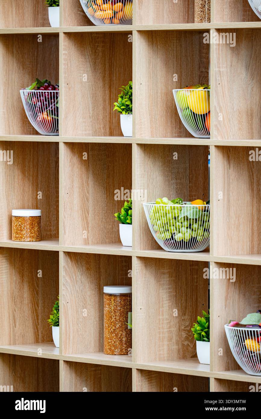 Holzregal mit frischem Obst, gesundem Essen und dekorativen Pflanzen Stockfoto