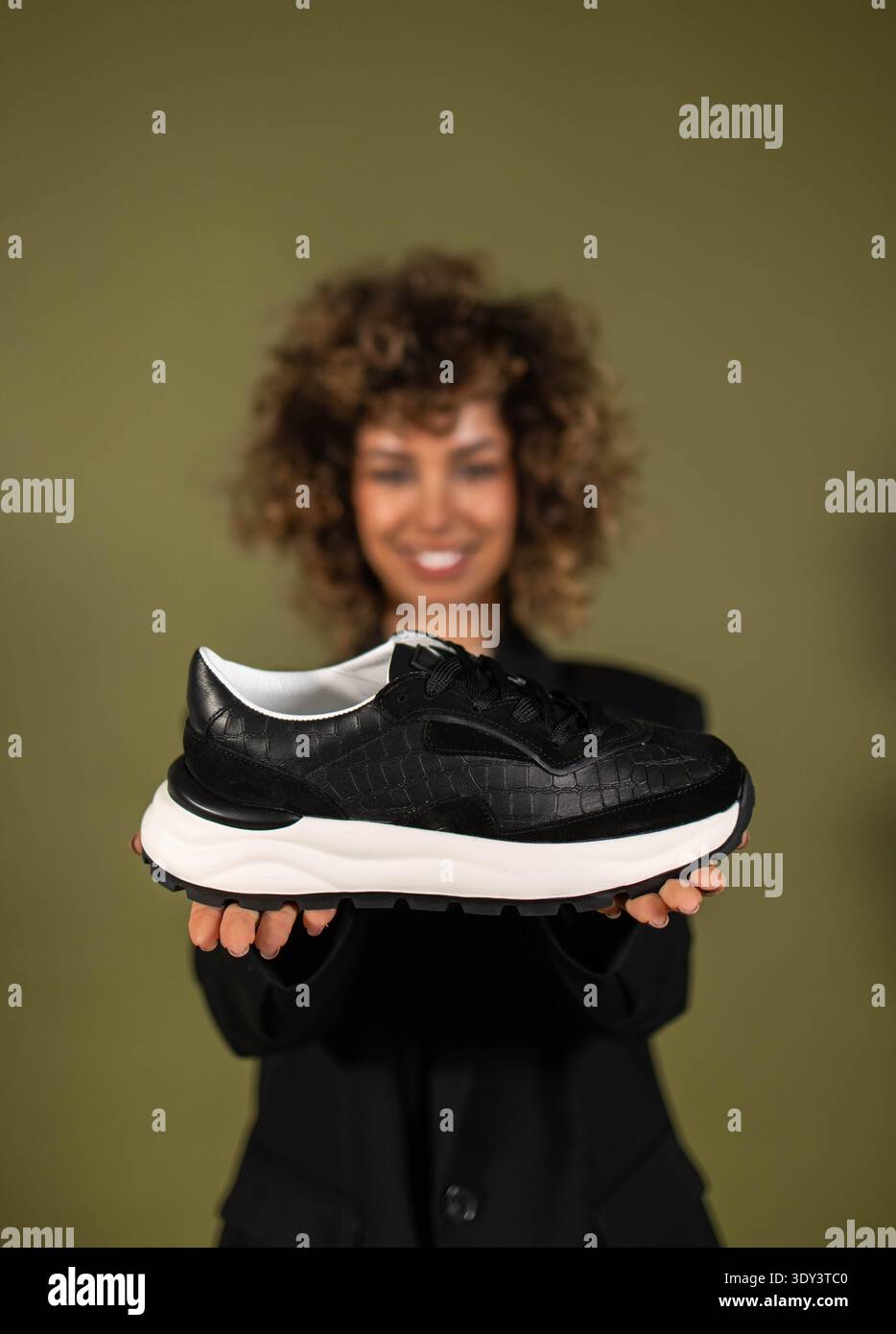 Eine Frau posiert und hält ein Paar Turnschuhe in der Hand Stockfoto