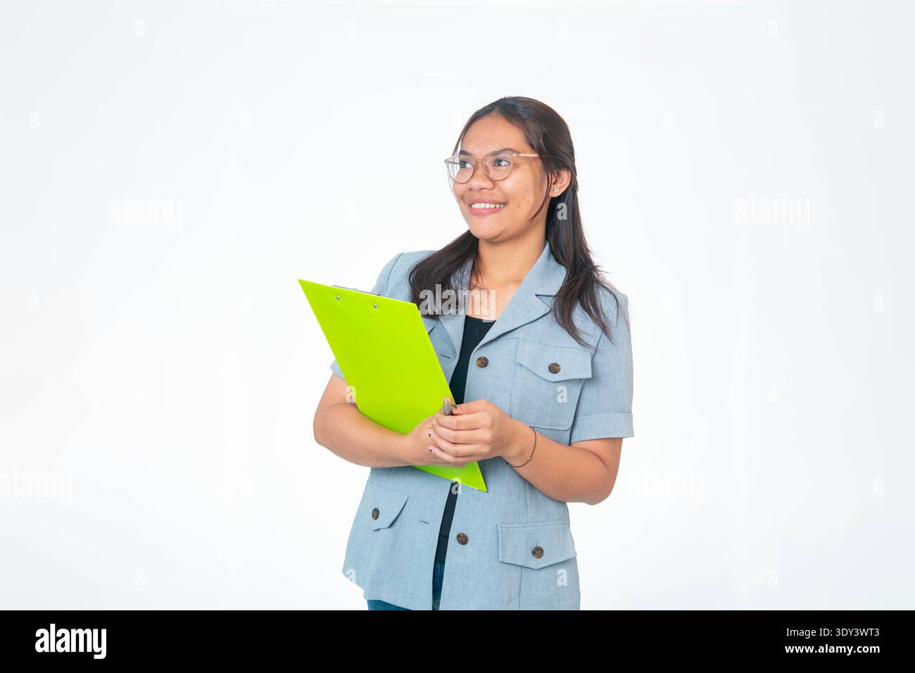 Indonesische Profi-Frau in grauem Blazer, die grüne Zwischenablage hält und zur Seite blickt. Isoliert auf weißem Hintergrund mit Kopierraum für Geschäftsleute Stockfoto