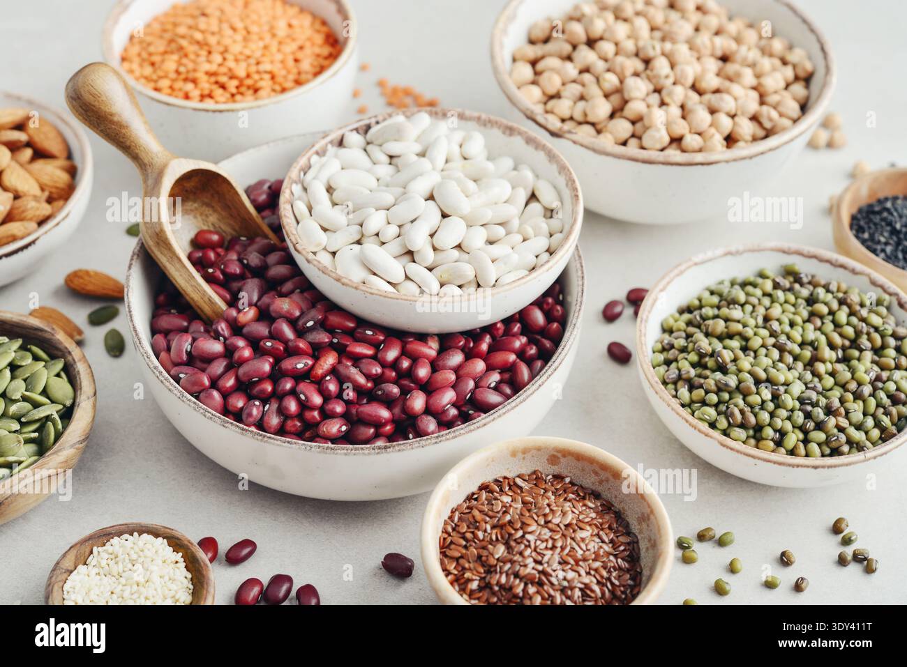 Vegane Proteinquelle. Leguminosen – Linsen, Kichererbsen, Bohnen, grüne Mungbohnen, Samen, und Nüsse auf hellem Hintergrund. Stockfoto