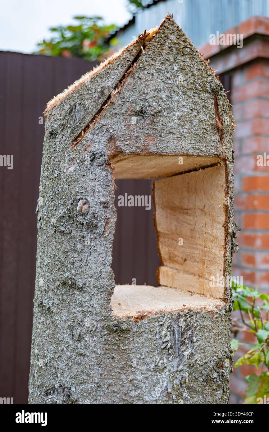 Handgeschnitzte rustikale Vogelfutteranlage aus Holz aus Baumstamm mit rauer Rinde und strukturiertem Holz Stockfoto