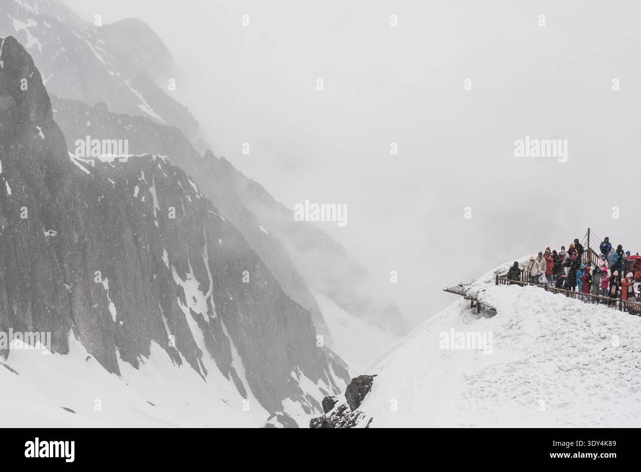 LIJIANG, YUNNAN, CHINA - 12. APRIL 2025: Touristen versammeln sich auf einer schneebedeckten Aussichtsplattform des Jade Dragon Snow Mountain, um Fotos zu machen Stockfoto