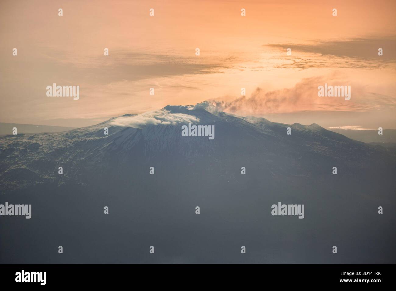 Blick aus der Vogelperspektive auf den Ätna mit einer vulkanischen Wolke, die vom Gipfel abhängt, vor einem goldenen Sonnenuntergang auf dem Ionischen Meer. Stockfoto