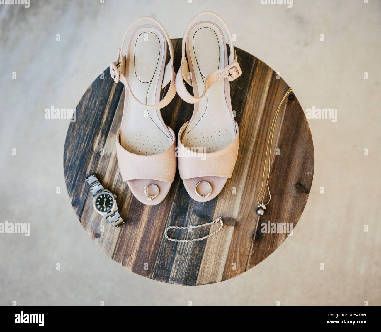 Elegante Brautschuhe mit Hochzeitsschmuck auf einem Holztisch. Details zur Hochzeitsvorbereitung mit Fersen, Armband und Accessoires. Stockfoto