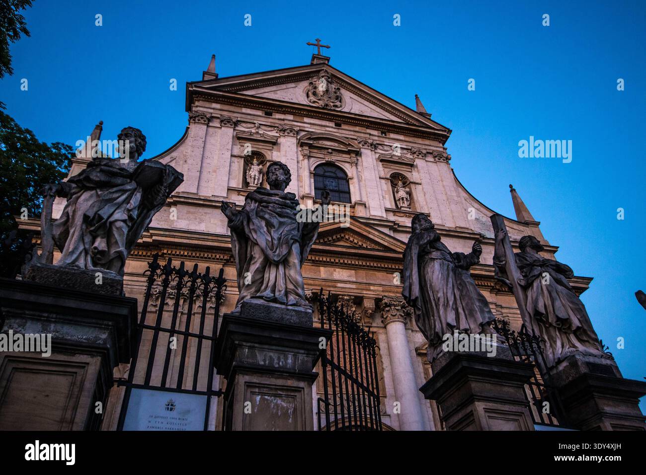 Statuen der Apostel, die sich vor der barocken Fassade der Peter-und-Paul-Kirche abheben, die in goldenem Sonnenlicht des Abends getaucht ist, Krakau, Polen. Stockfoto