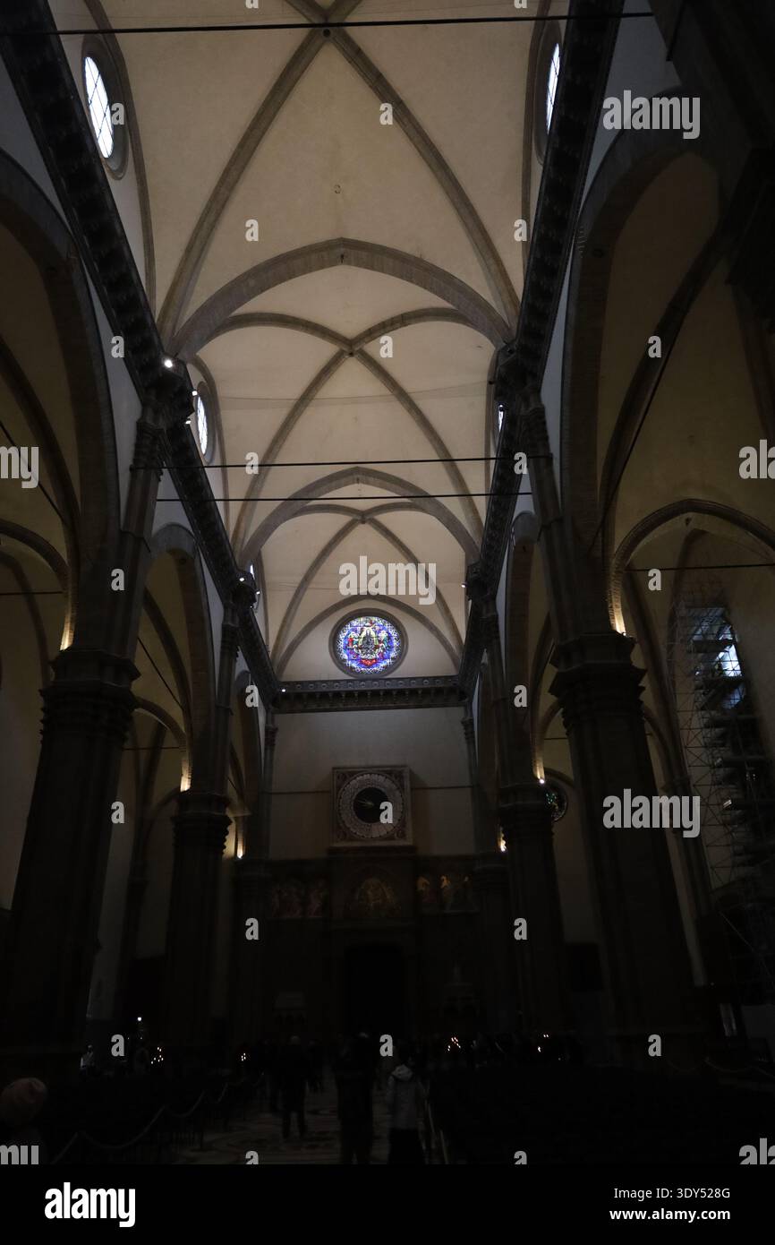 Innenansicht eines gotischen Kirchenschiffs mit spitzen Bögen, geriffelten Gewölben, Buntglasfenstern und gedämpfter atmosphärischer Beleuchtung. Stockfoto