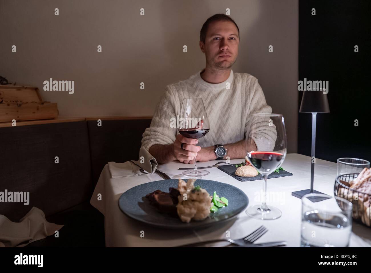 Edler Esstisch mit Rotwein und Lampe im Dolomites Hotel Stockfoto