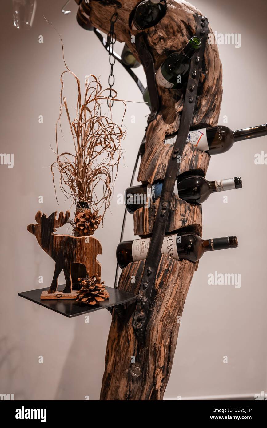 Weinregal aus skulpturalem Baumstamm mit Eisenbändern und alpenländischem Dekor Stockfoto