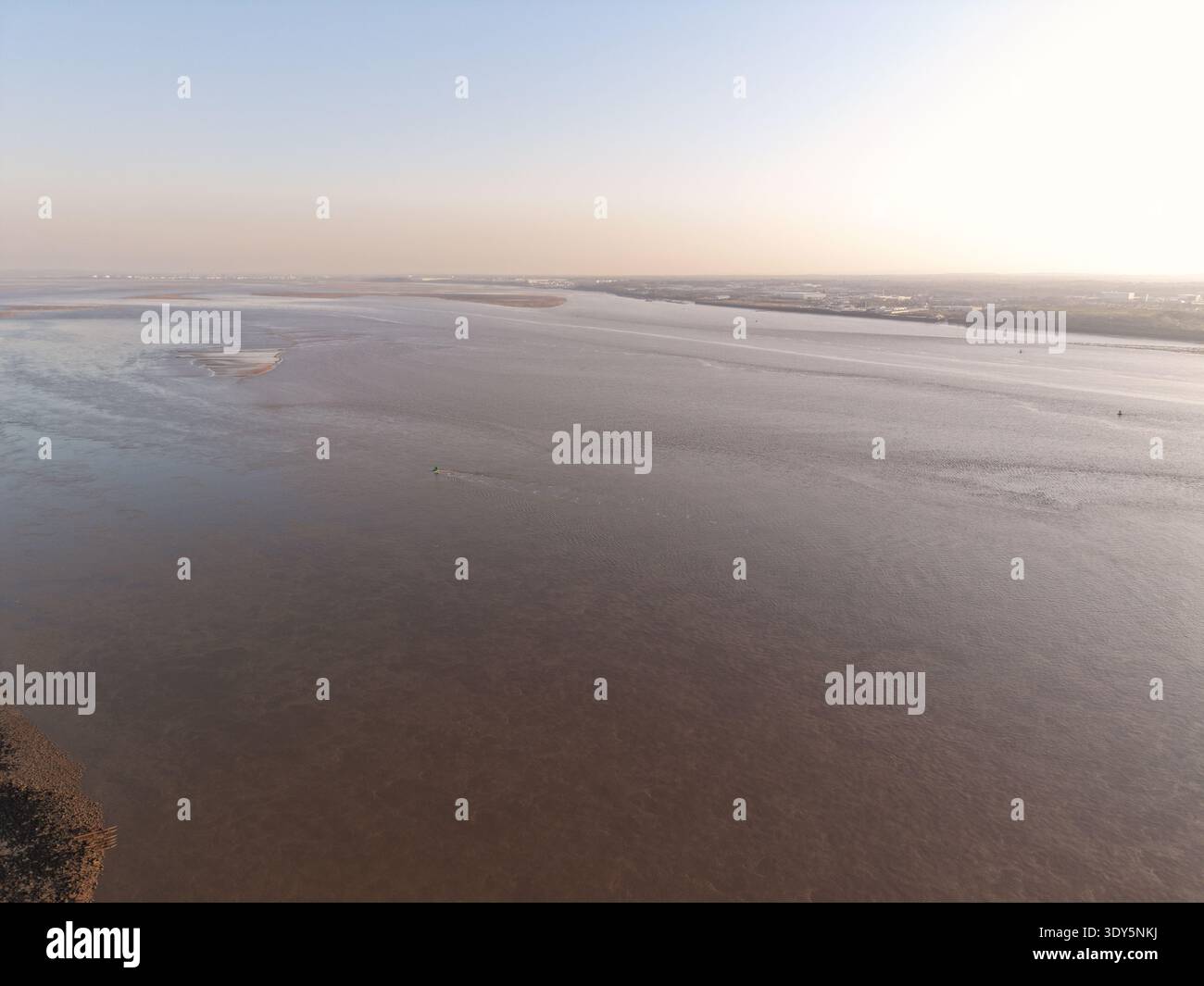 Luftaufnahme mit Gezeitenwasser über den Fluss Mersey mit der Skyline von Liverpool in der Ferne. Stockfoto