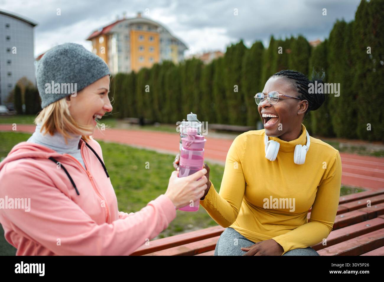 Verschiedene Freunde lachen und teilen sich Wasser auf der Sportstrecke Stockfoto