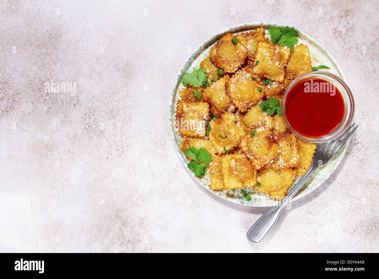 Gebratene Ravioli mit Parmesankäse, serviert mit roter Sauce und garniert mit Kräutern, auf hellem Hintergrund, keine Leute Stockfoto