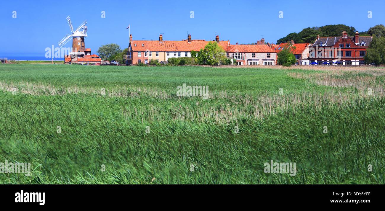 Die Windmühle in Norfolk, England, steht neben Häusern und Feldern in Küstennähe und zeigt das ländliche Leben und die Küstenlandschaft Stockfoto
