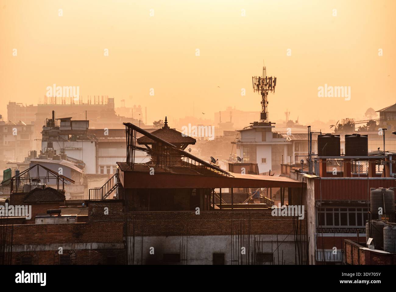 Die urbane Skyline auf dem Dach von Kathmandu bei Sonnenuntergang mit Kommunikationstürmen und Dunst schafft eine einzigartige Atmosphäre Stockfoto