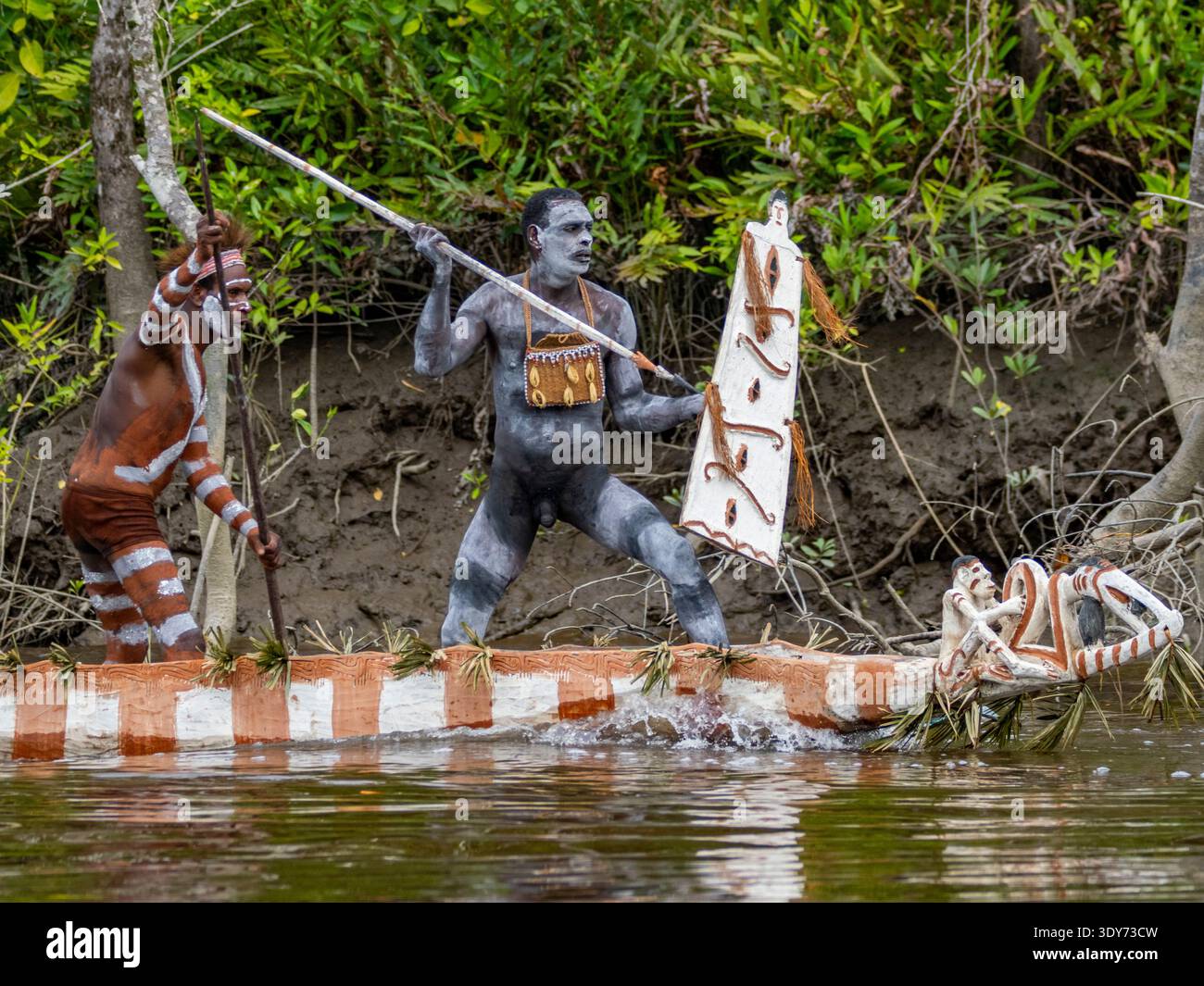 Männliche Paddler führen eine rituelle Begrüßungszeremonie auf dem Fluss während einer festlichen Veranstaltung in Süd-Papua, Indonesien, durch Stockfoto