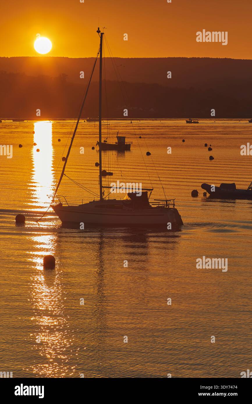 Sonnenuntergang über der Flussmündung des Flusses exe mit Booten, die das Sonnenlicht reflektieren, in Exmouth, Devon Stockfoto