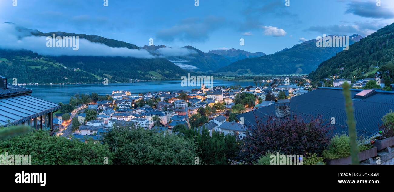 Blick auf Zell am See und den Zeller See in der Abenddämmerung in Salzburg Österreich mit Lichtern, die auf dem Wasser reflektieren Stockfoto