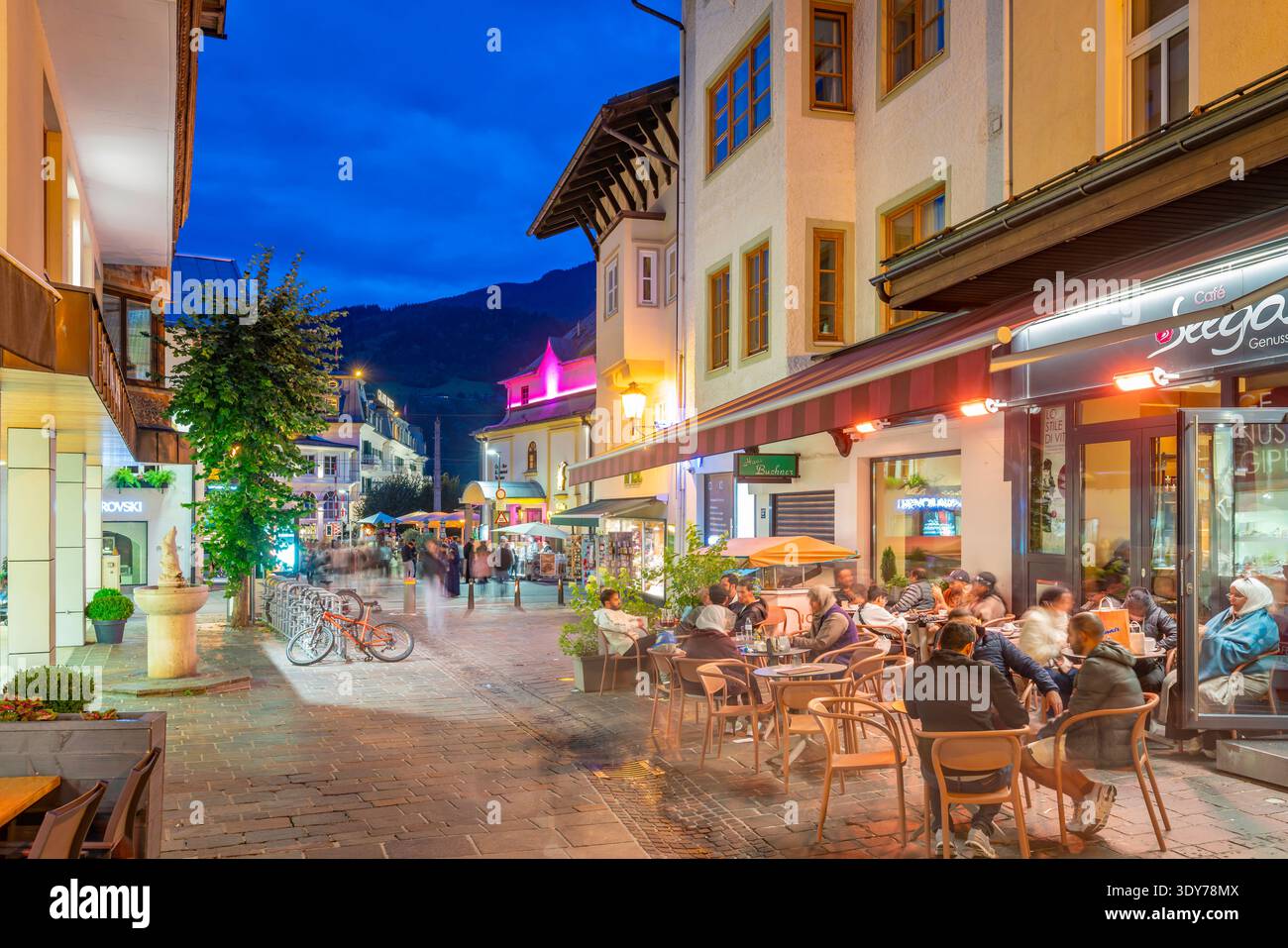 Abendszene mit Speisen und Getränken in einem belebten Restaurant in Zell am See unter Sonnenuntergang Stockfoto