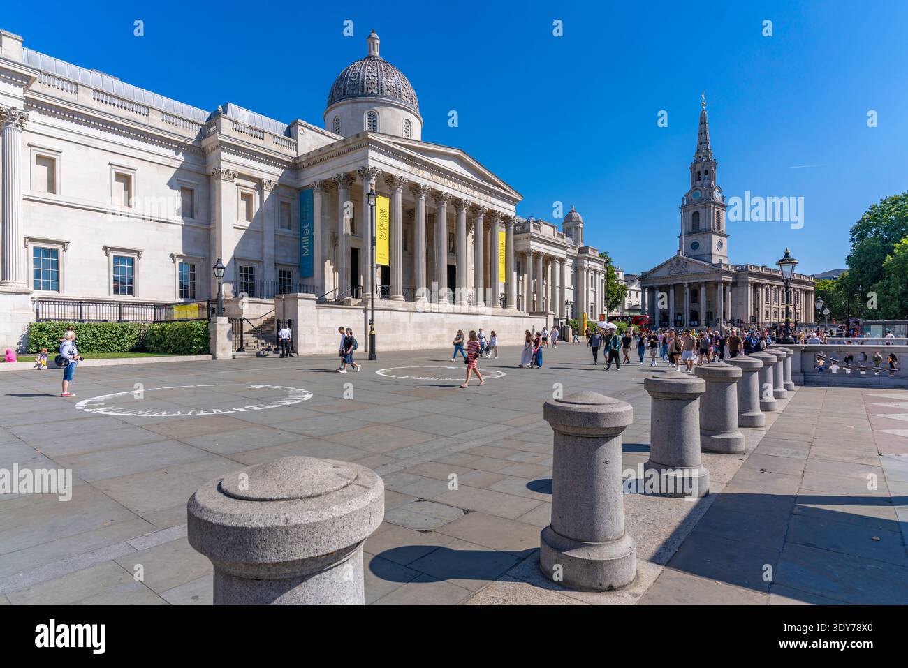 Besucher erkunden die National Gallery und den Trafalgar Square im Sommer in London mit klarem, blauem Himmel und hellem Sonnenschein Stockfoto