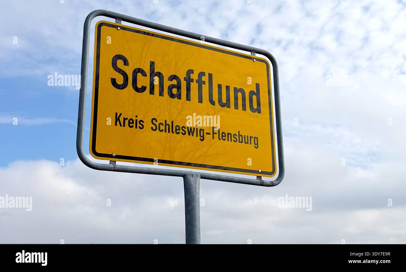 Schafflund Stadtschild im Landkreis Schleswig-Flensburg, mit gelbem Hintergrund und schwarzem Text vor bewölktem Himmel Stockfoto