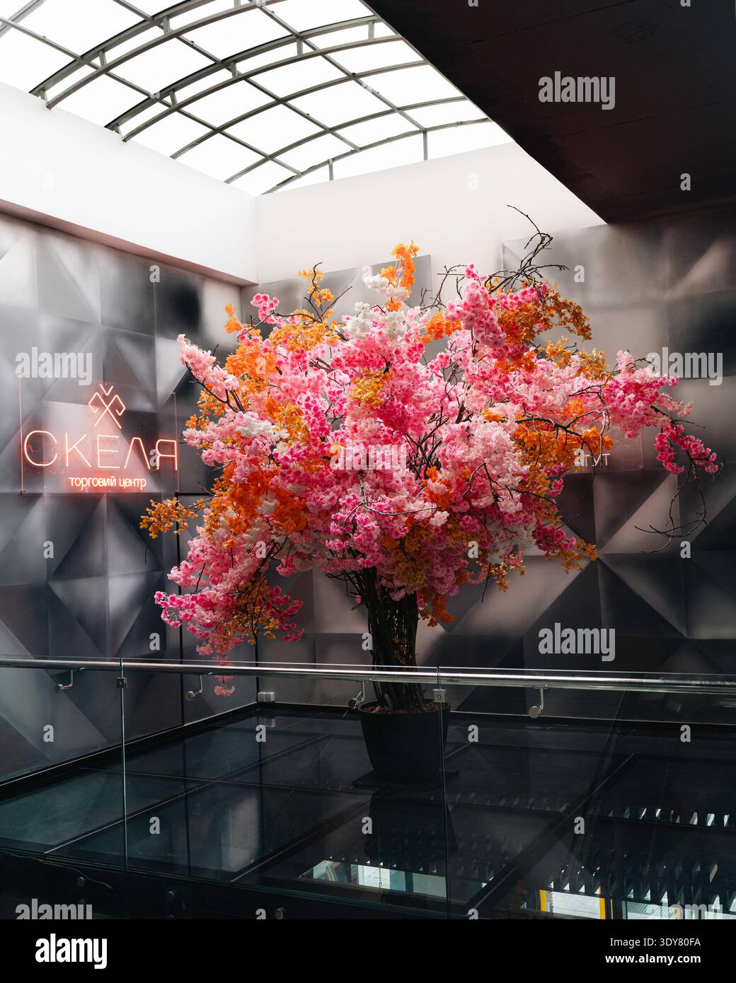 Dekorativer künstlicher Blumenbaum in einem Einkaufszentrum in Jaremche, Karpaten, Ukraine. Moderner Innenraum mit geometrischer Wand p Stockfoto