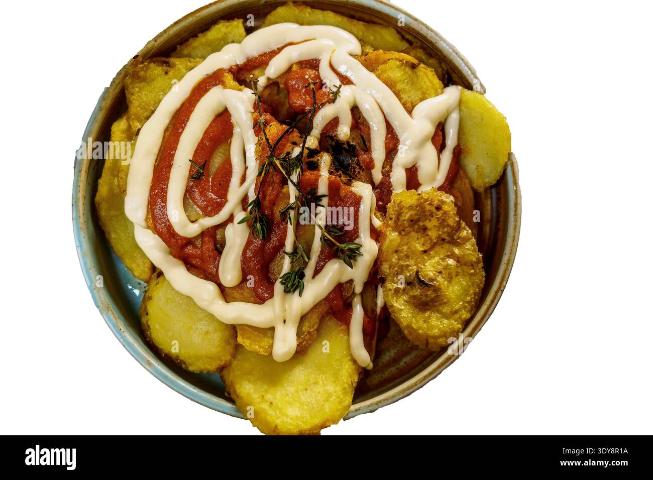 Blick von oben auf die Schüssel mit gebratenen Kartoffelscheiben, belegt mit Wurst, Tomatensauce, Mayonnaise-Nieseln und Kräutern isoliert auf weißem Hintergrund. Stockfoto