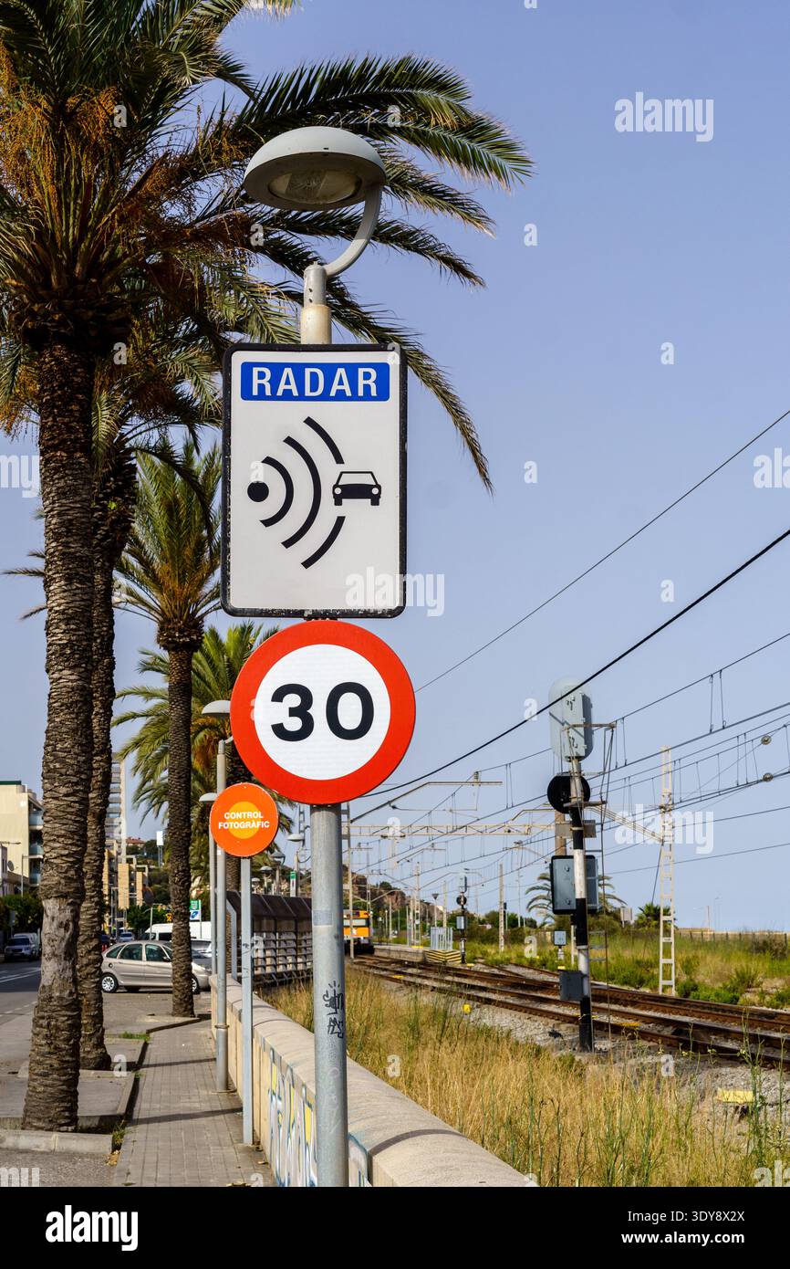 Straßenszene mit Palmen, Radar-Geschwindigkeitsschild und 30 km/h-Grenze in der Nähe von Bahngleisen unter klarem Himmel Stockfoto