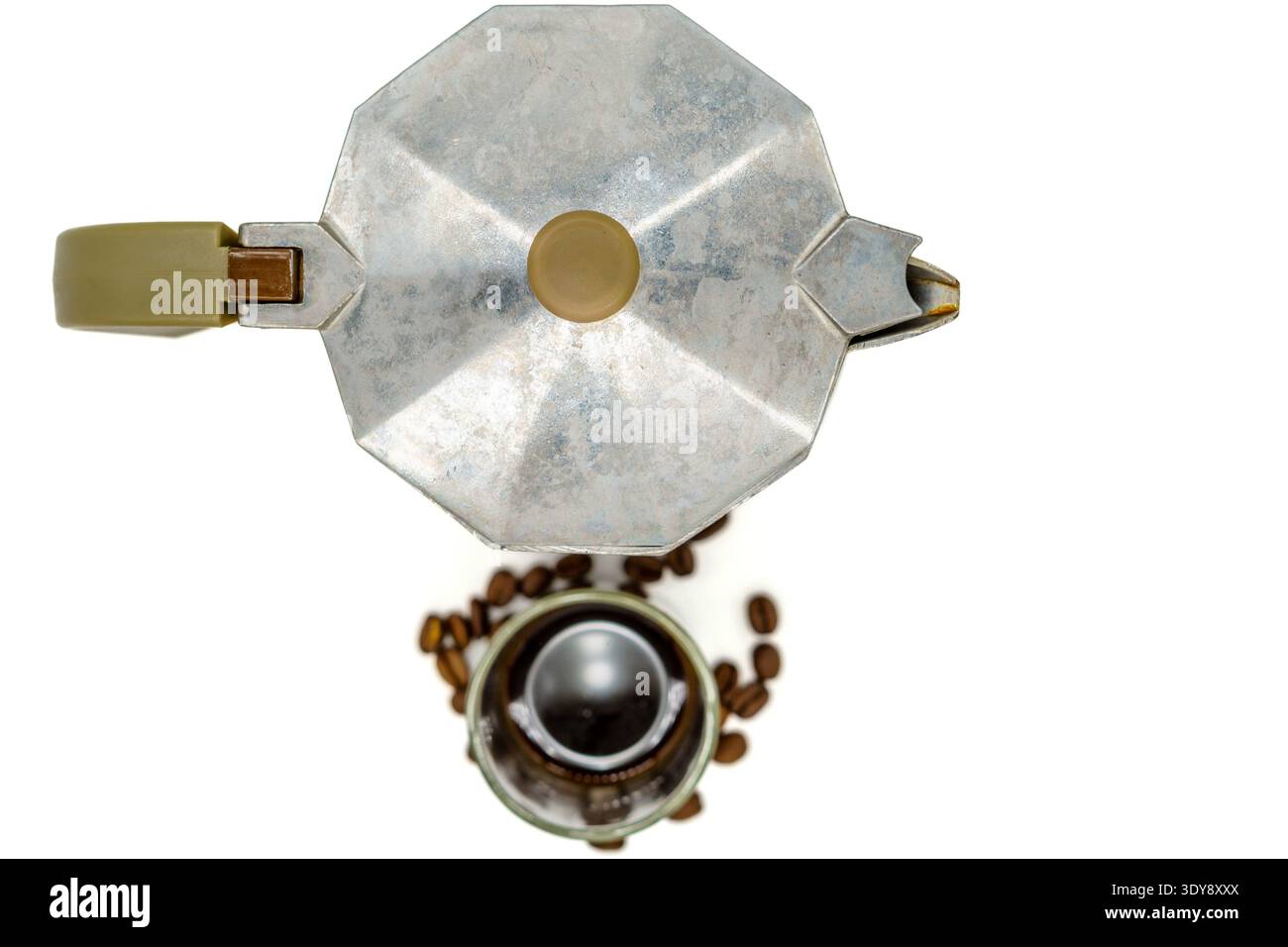 Blick von oben auf eine silberne Espressomaschine mit Kaffeebohnen und einer kleinen Tasse darunter auf weißem Hintergrund Stockfoto