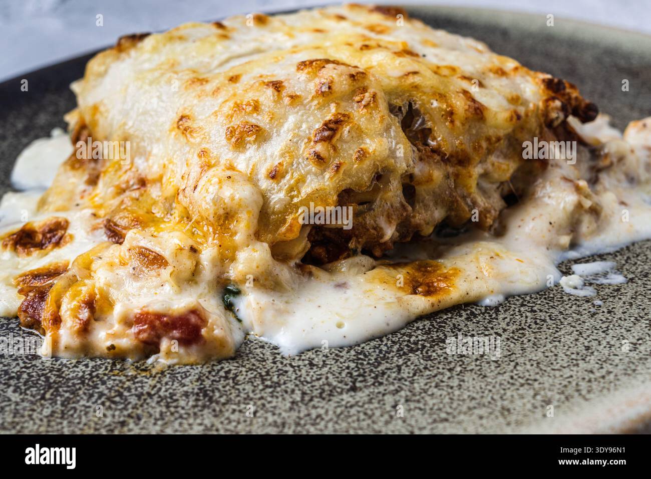 Lasagne mit geschmolzenem Käse, serviert in einer braunen Steingut-Schale. Typisch italienische und mediterrane Küche Stockfoto