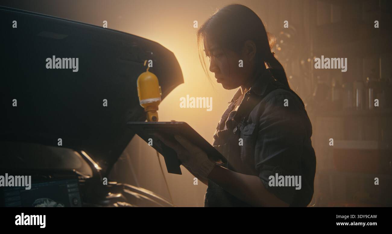 Professionelle Technikerin beim Zurücksetzen des Autocomputers und Eingeben von Wartungsdaten mit dem digitalen Tablet in der modernen Werkstatt. Effizienzkonzept digitaler Werkzeuge in der modernen Kfz-Pflege. Stockfoto