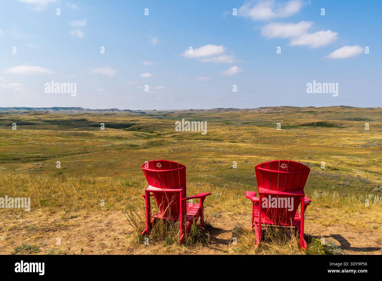 Fire Mountain, SK CANADA - 6. August 2024: Rote Stühle von Park's Canada mit Blick auf die Landschaft der Prärie-Badlands. Stockfoto