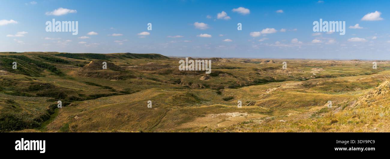Die Badlands des Grasslands National Park bieten einen weiten Panoramablick auf erodierte Formationen unter hellem Himmel. Stockfoto