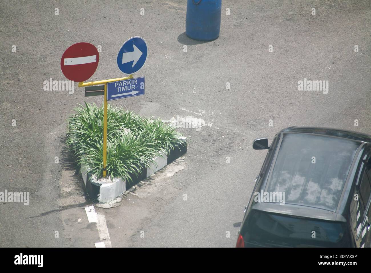 Stoppschild und Pfeilschild zum Parkplatz mit Blick aus der Vogelperspektive auf das schwarze Auto Stockfoto