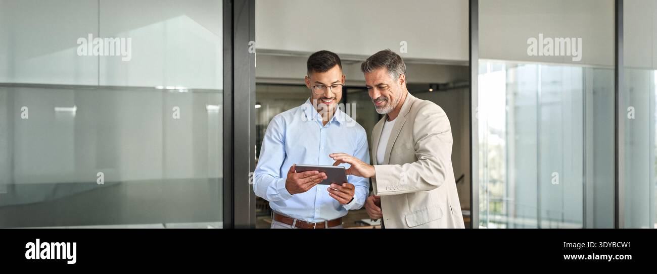 Team aus zwei glücklichen Geschäftsleuten, die im Büro mit einem digitalen Tablet arbeiten. Stockfoto
