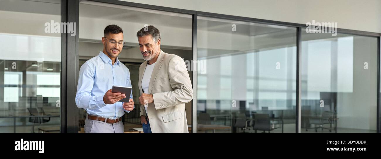 Team aus zwei glücklichen Geschäftsleuten, die im Büro mit einem digitalen Tablet arbeiten. Stockfoto