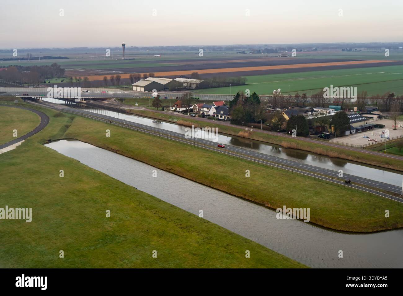 Höhenpanorama über die Niederlande mit Entwässerungskanal neben der Autobahn, grünen Ackerflächen und ländlichen Häusern, die die Infrastruktur-pla veranschaulichen Stockfoto