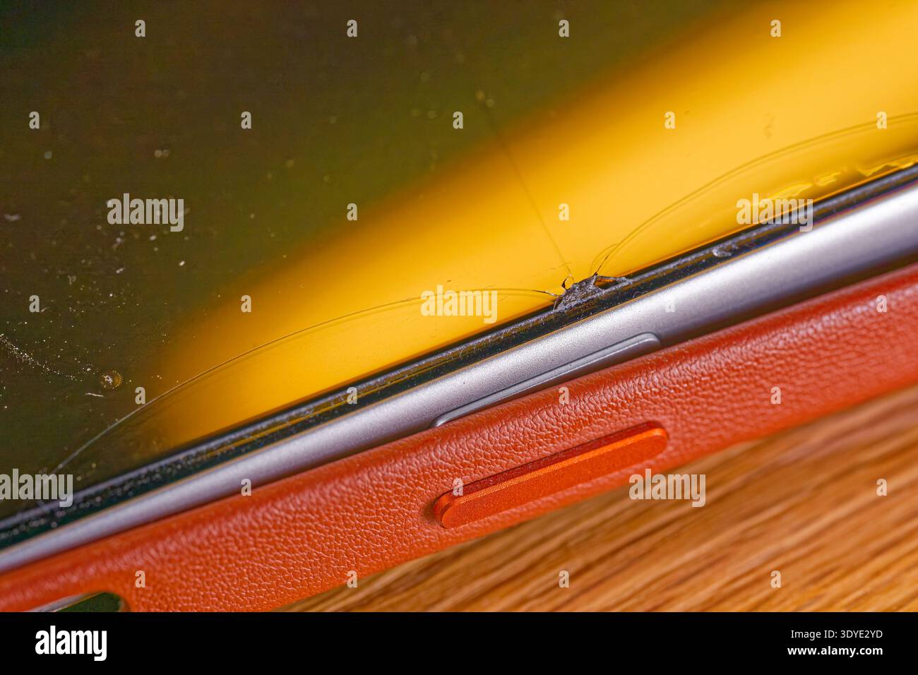 Ein Smartphone mit einem gerissenen Bildschirm und einer strukturierten Schutzhülle wird mit sichtbaren Beschädigungen und Kratzern auf der Displayoberfläche gezeigt. Stockfoto