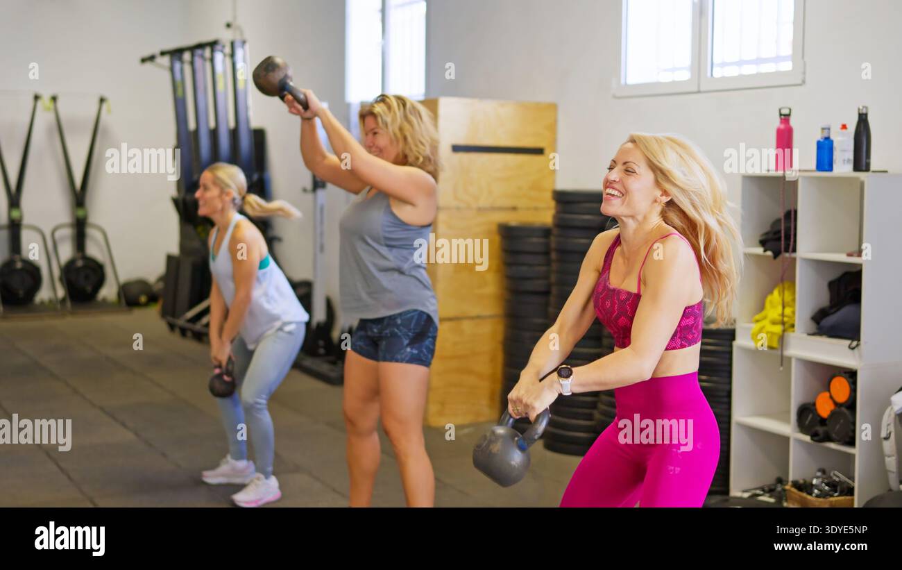 Frauen, die Kettlebells während intensivem Fitness-Training im Fitnessstudio spielen Stockfoto