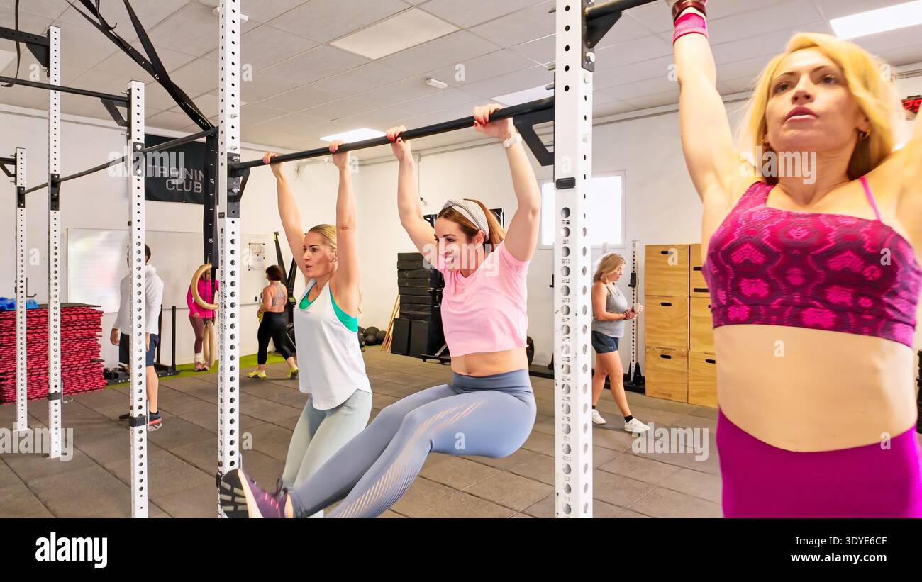 Frauen, die ihr Körpergewicht beim Kippen im Fitnessstudio heben Stockfoto