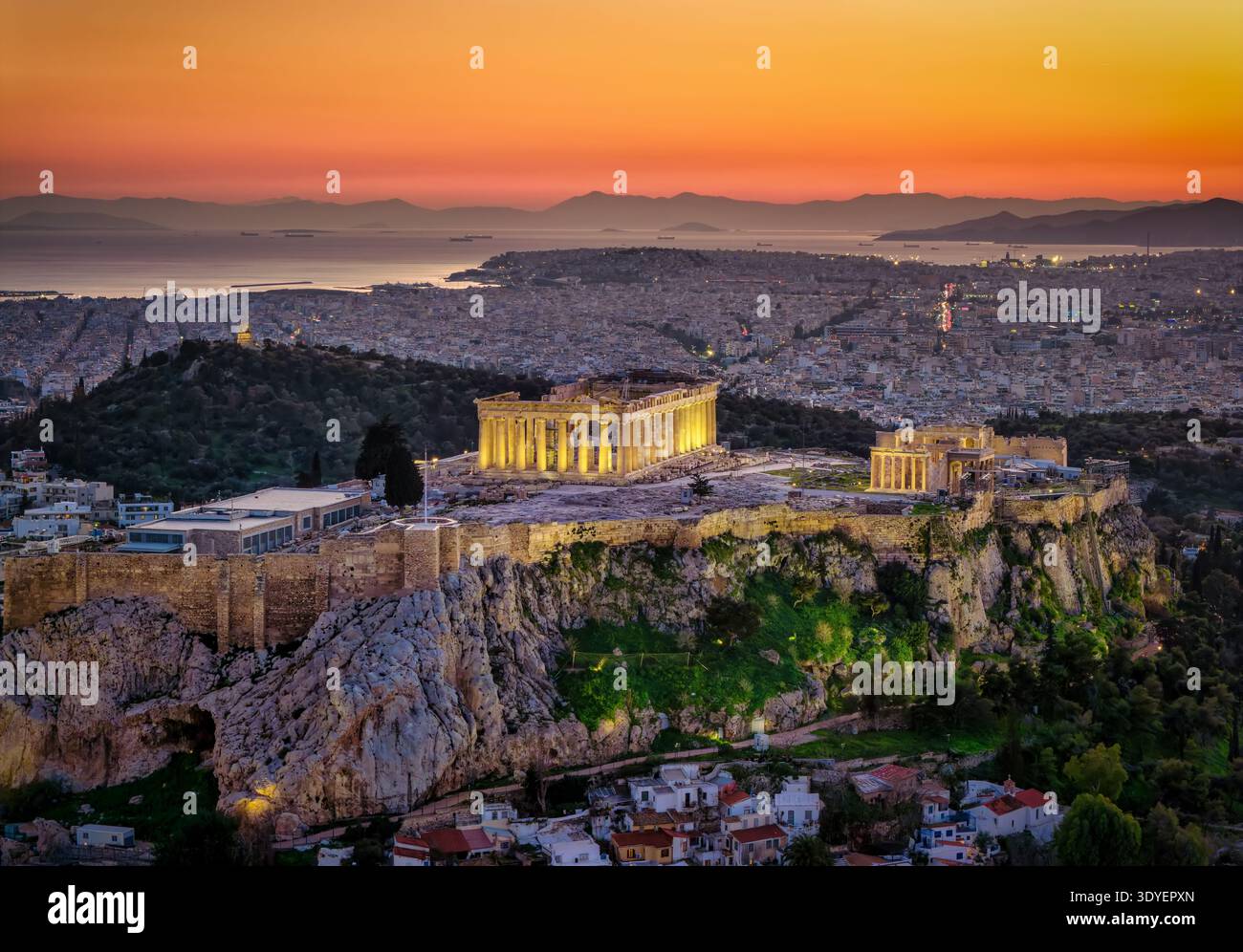 Luftaufnahme des beleuchteten Parthenon-Tempels an der Akropolis von Athen, Griechenland, während der Dämmerung mit der Skyline der Stadt im Hintergrund Stockfoto