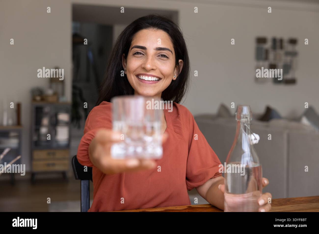 Frau, die ein Glas Wasser mit einem Lächeln anbietet Stockfoto