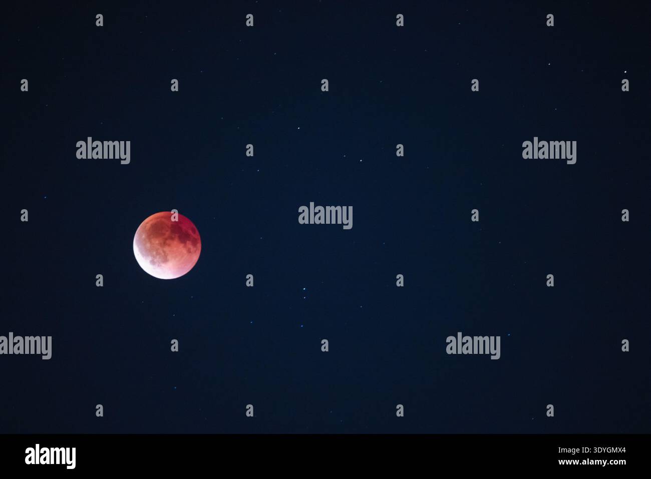 Blutmond während Mondfinsternis glühend rot am Nachthimmel mit sichtbaren Sternen Stockfoto