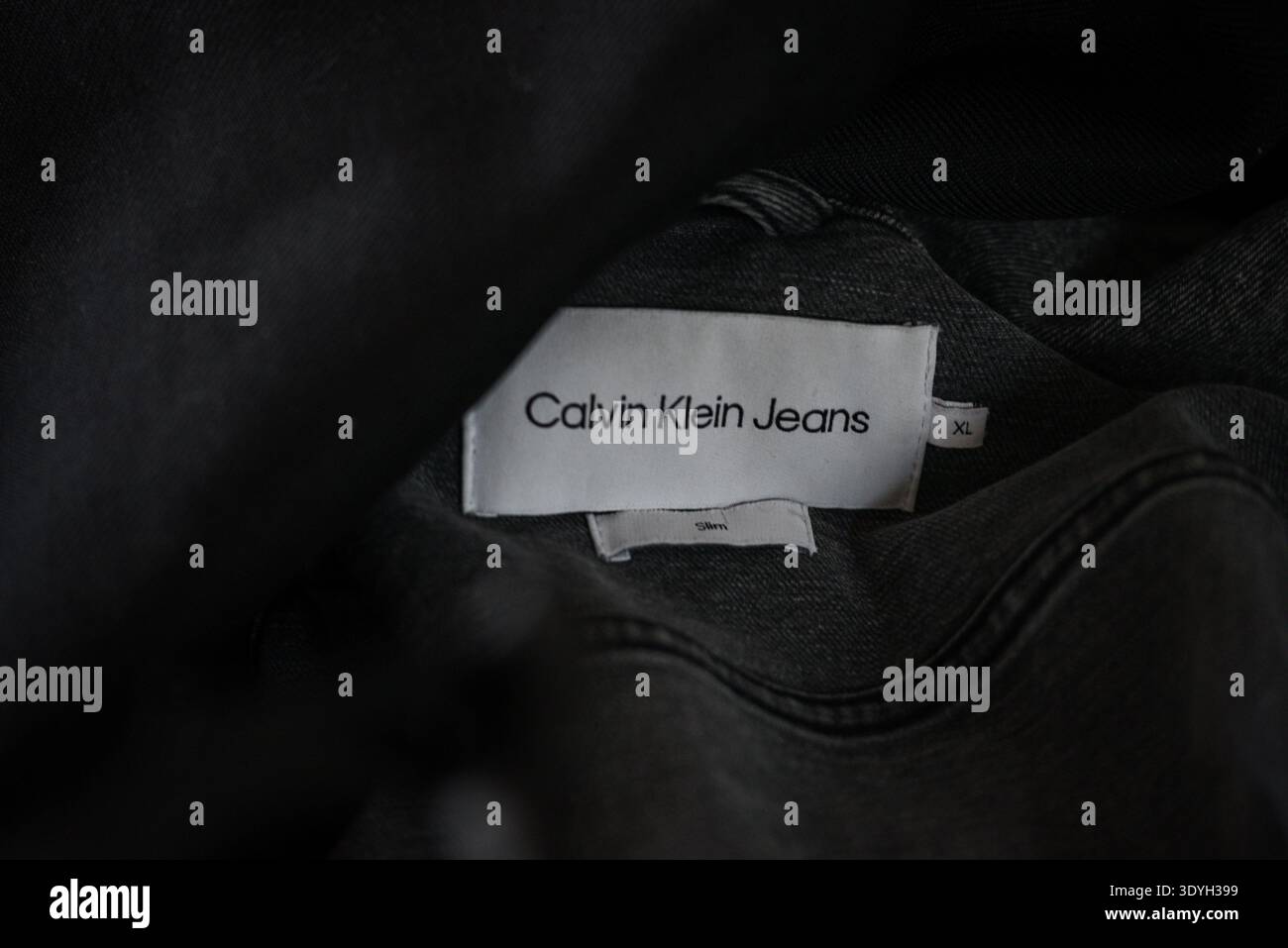 Ventspils, Lettland - 5. März 2026: Nahaufnahme eines Bekleidungsetiketts von Calvin Klein Jeans in einer schwarzen Jacke. Detailansicht des Markenkennzeichens, S. Stockfoto