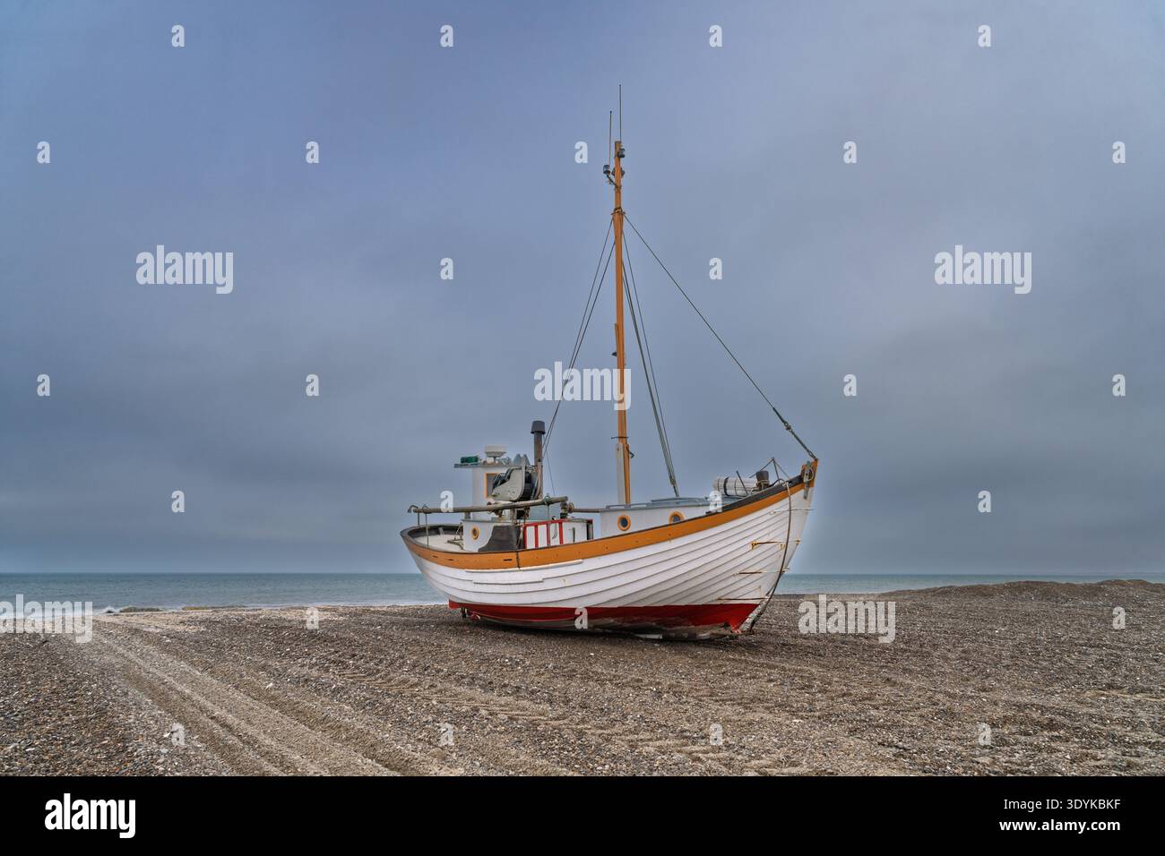 Zwei Fischerboote aus Holz am Strand ruhen an einem Kieselstrand unter einem bewölkten Himmel und vermitteln eine ruhige Küstenatmosphäre, verwitterte Texturen und nautica Stockfoto