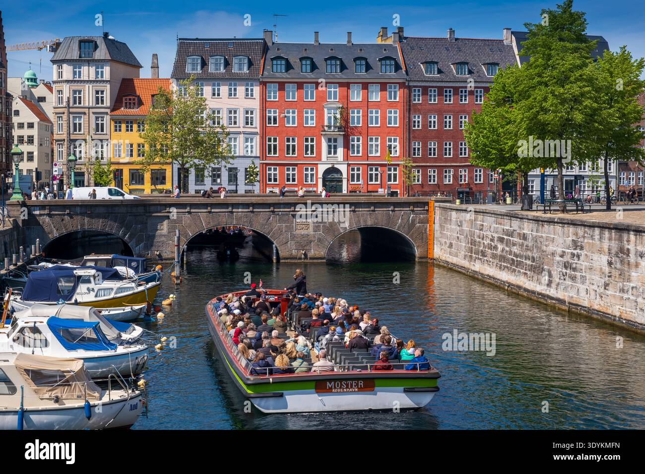 Kanalrundfahrt mit Touristen, die an der historischen Brücke und den farbenfrohen Häusern entlang des Frederiksholms-Kanals, Kopenhagen, Dänemark, vorbeifahren Stockfoto