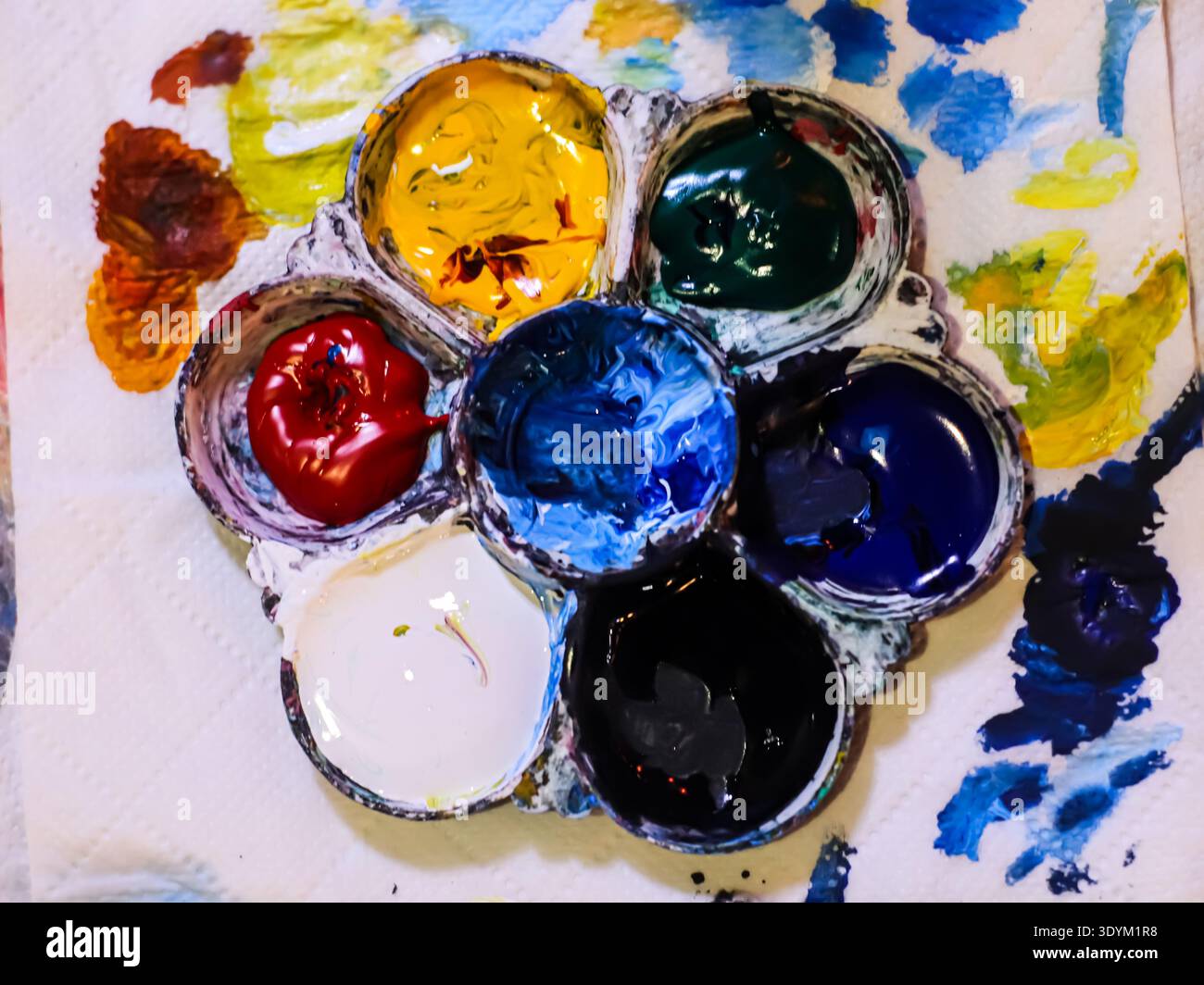 Unordentliche Aquarellpalette mit Farbspritzern und Flecken, die künstlerischen Prozess, Kreativität und ausdrucksstarken Hintergrund repräsentieren. Stockfoto