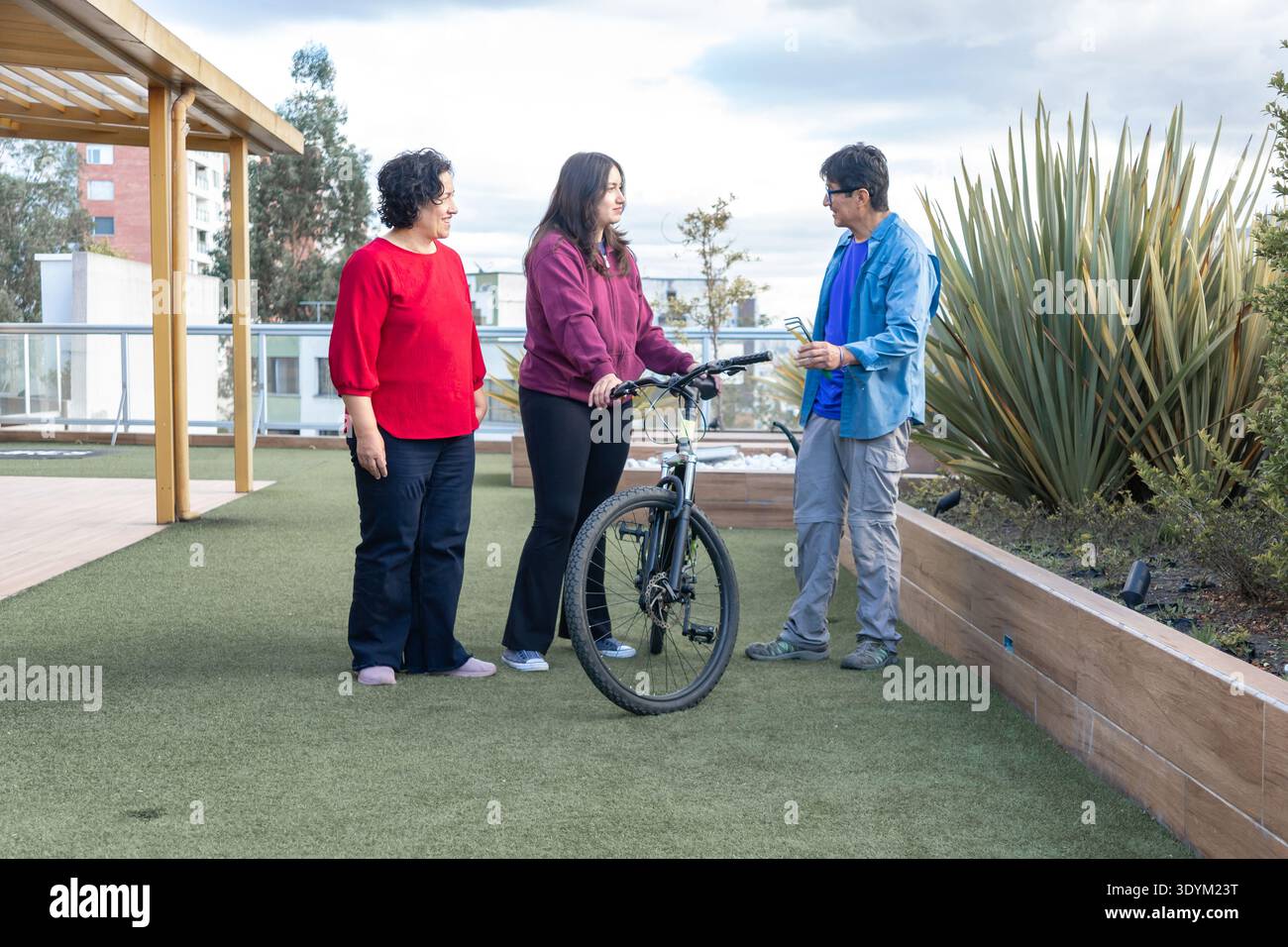 Familienmitglieder diskutieren auf einem urbanen Dachgarten mit dem Fahrrad Stockfoto