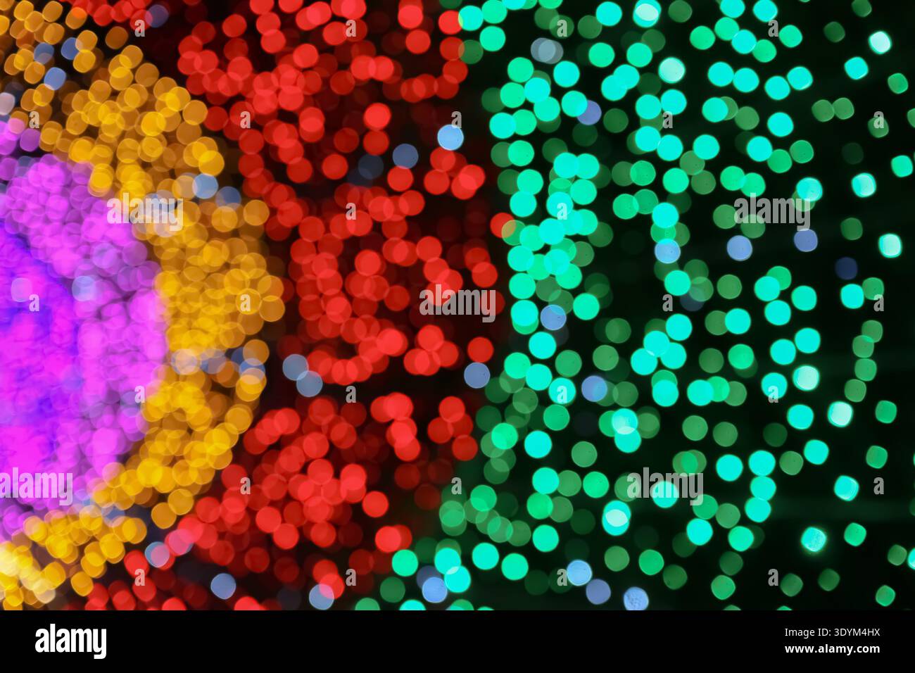 Farbenfrohe Bokeh-Lichter abstrakter Hintergrund mit grünen roten gelben und violetten Zonen schaffen eine festliche und verspielte visuelle Atmosphäre. Stockfoto