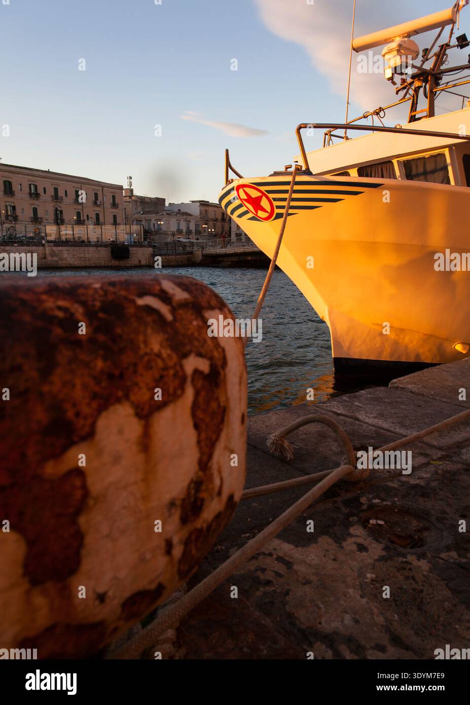 Ein weißes Arbeitsboot, das in einem Hafen an einem rostigen Schiffspoller ankert, mit Radartechnologie an Bord Stockfoto