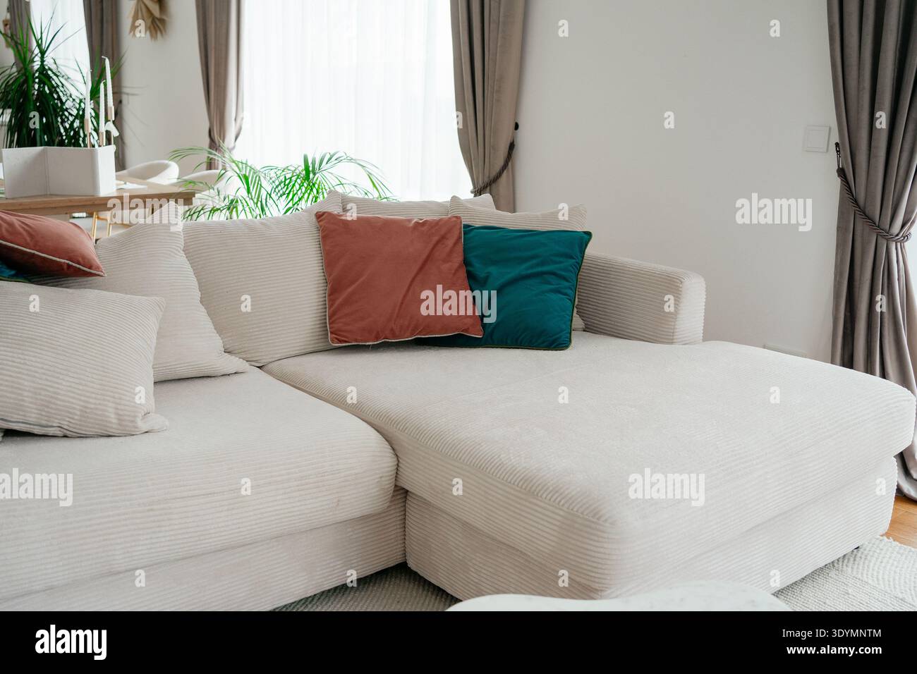 Modernes Wohnzimmer mit weißem Sofa und farbenfrohen dekorativen Kissen. Heller, komfortabler Raum mit elegantem, minimalem Design. Konzept des Heims Stockfoto