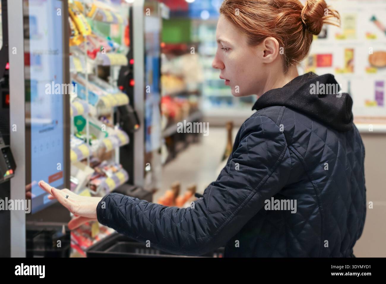 Seitenansicht einer jungen Frau, die Artikel aus Automaten im Supermarkt nimmt Stockfoto